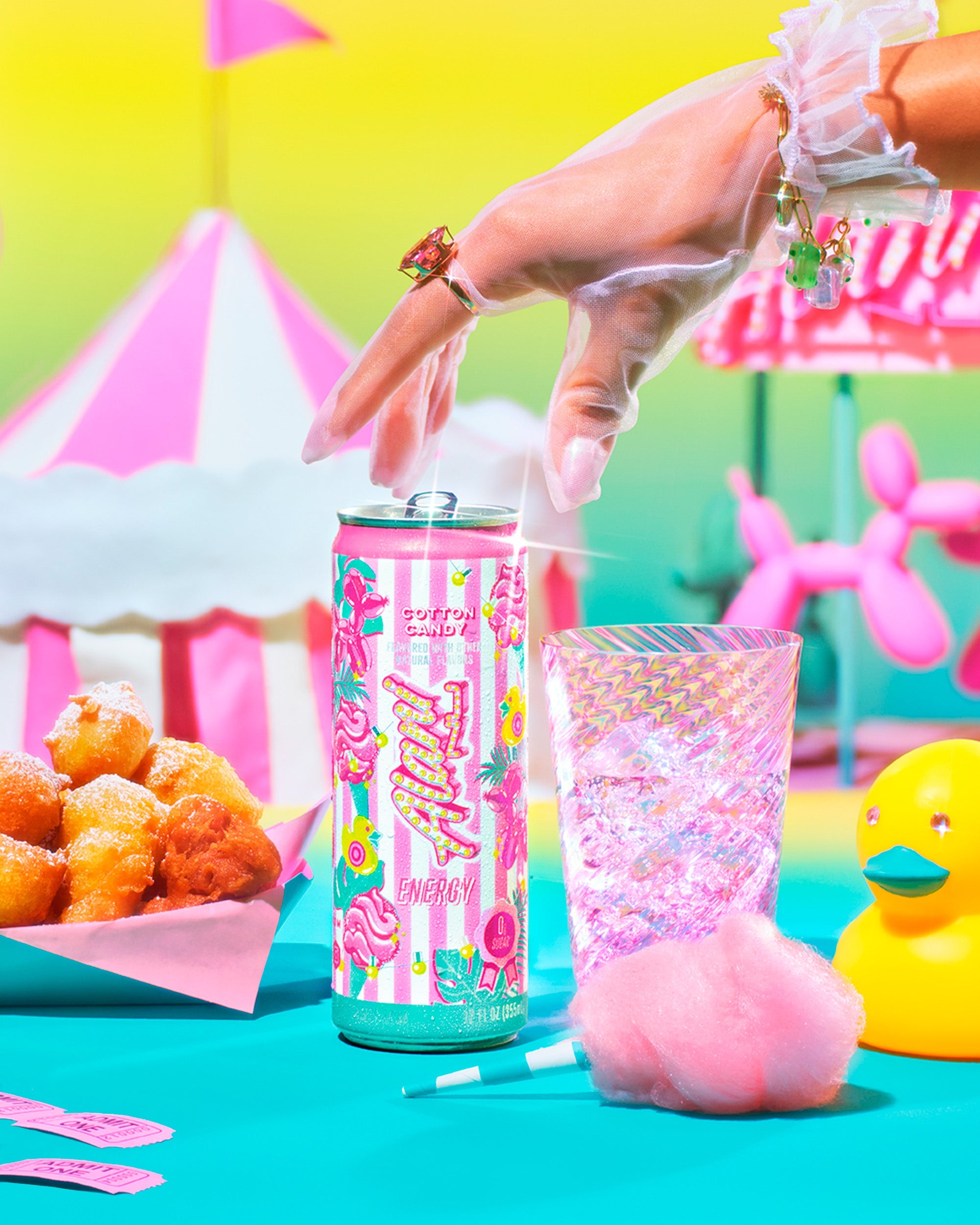 A woman's gloved hand reaching for a limited-edition Cotton Candy Alani Energy. Carnival treats, rides, and tents set the whimsical scene.